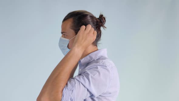 Demonstration of Young Man Putting on Protective Face Mask, Closeup Profile alt