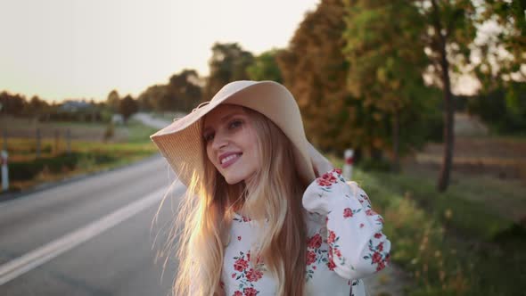 Traveler Woman Hitchhiking on a Sunny Road and Walking. alt