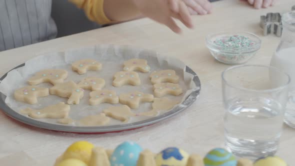 Hands of Girl Taking Baking Sheet with Easter Cookies alt