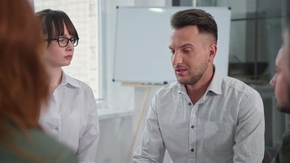 Portrait of a Young Sad Man Talking About His Experiences to People During a Group Psychotherapy alt