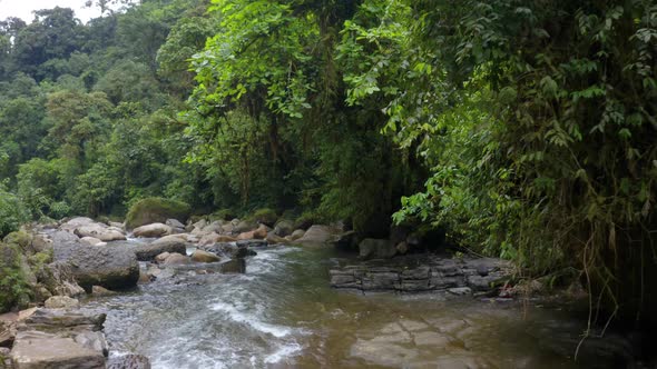 River Anzu in the Andes, a river with large boulders lined with trees alt
