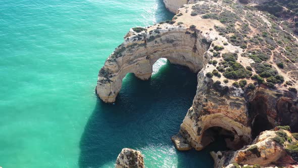 Ocean eroded rock arch formations in Marinha Beach south of Portugal, Aerial approach shot alt