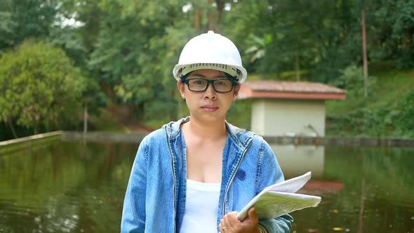 emale ecologist in safety hat working and controlling a quality of water. alt