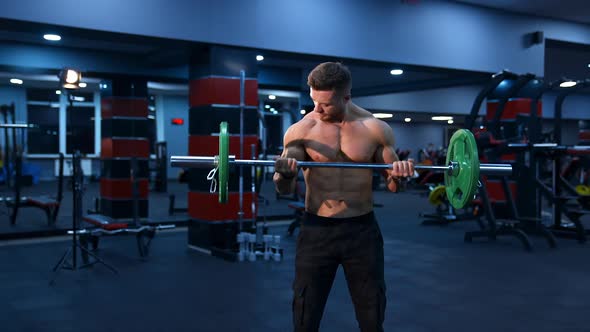 Athletic man in gym exercising with barbell. Bodybuilder with perfect body. Naked torso  alt