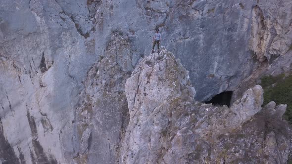Climber stands on high peak after ascending and looks out on amazing landscape of Turda Gorge on Sky alt