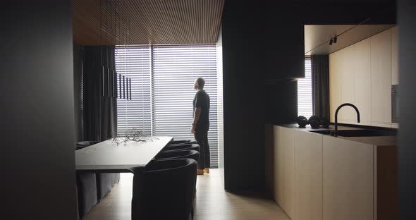 A Man Looks Out the Window Into a Apartment with an Modern Kitchen Interior alt