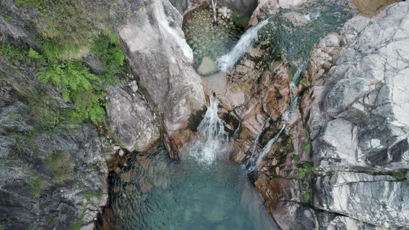 Top down slowly tilt up emerald Natural pool through small cascade, Portela do Homem - Gerês
