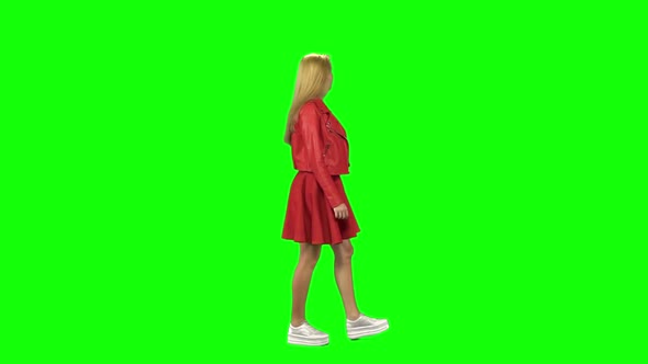 Blonde Girl Calmly Walking on Green Screen Background. Chroma Key. Profile View. Slow Motion alt