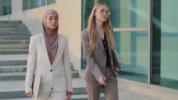 Serious Purposeful Colleagues Indian Girl in Hijab and Young European Woman Go to Office Together alt