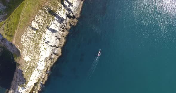 Lone fishing boat next to cliffs