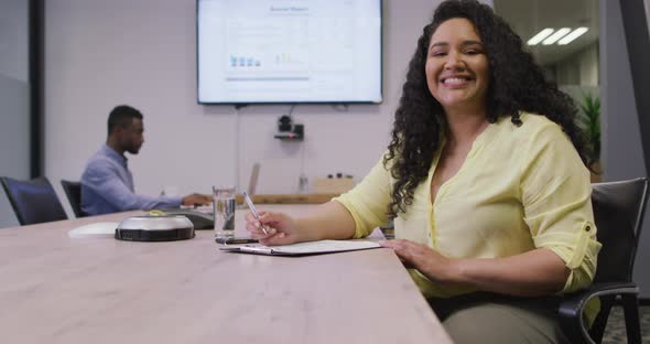Portrait of smiling biracial businesswoman looking at camera in modern office alt