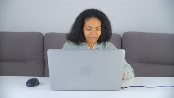 Black woman doing distant work on laptop computer at home during lockdown alt
