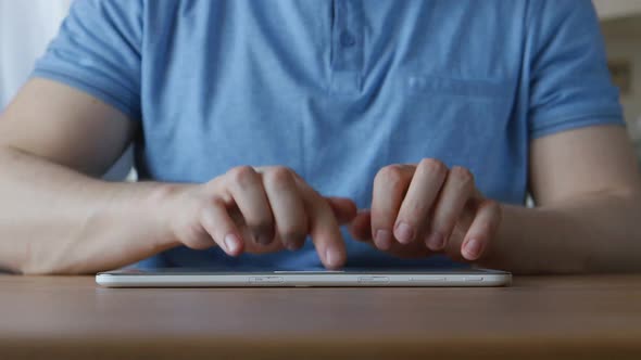 Hands Of Young Man Typing On A Tablet Pc At The Table At Home