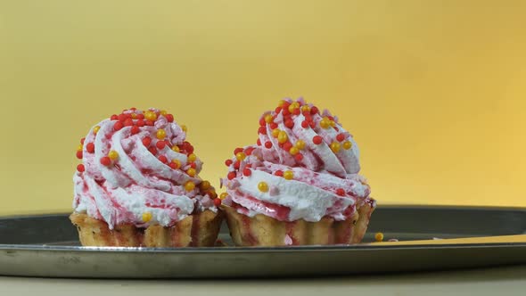 Two Cakes with Butter Cream Decorated with Round Colored Balls and Poured with Berry Syrup in a