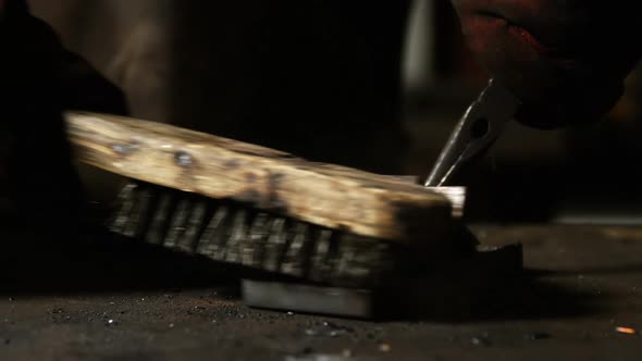 Hands of welder using wire brush on a piece of metal alt