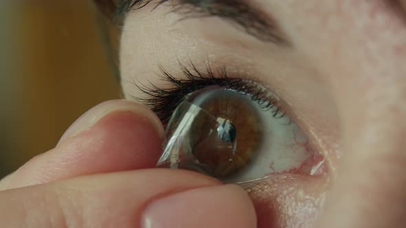 Woman with brown eyes removes a contact lens on her eye with her fingers, close-up alt