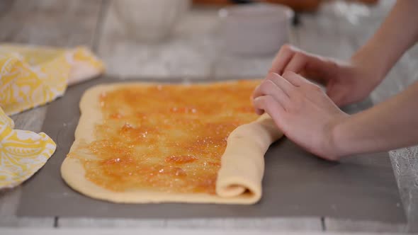 Closeup of a Woman Preparing Roll Buns with Apricot Jam