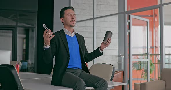 Young Serious Businessman Working in the Office Meditating in the Workplace with Closed Eyes alt