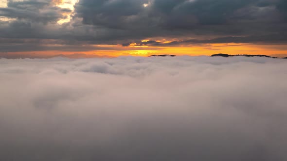 Drone flight over the clouds during sunrise.