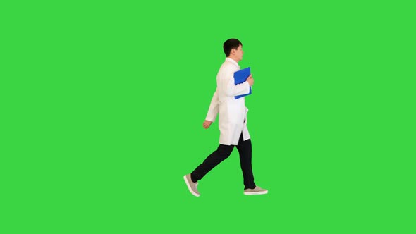 Young Asian Doctor Walks Fast with Documents in His Hand on a Green Screen Chroma Key