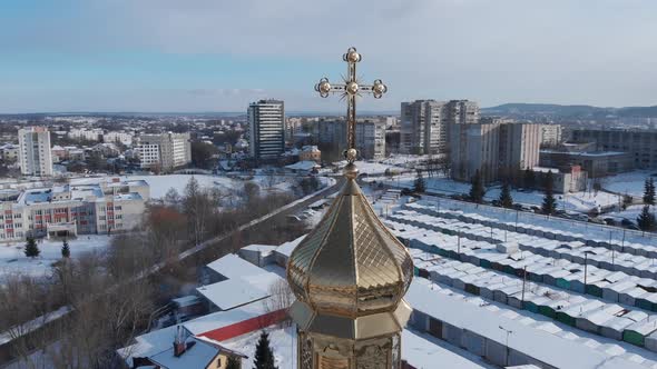 Aerial shot: flying around the goldened church dome with a cross.