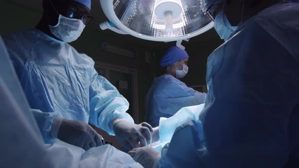 Mixed ethnic team of surgeons performing operation