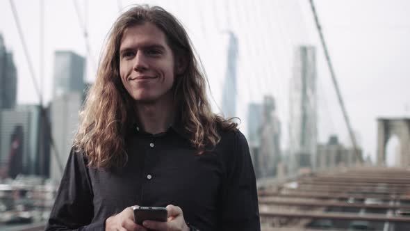 Adult Male with long hair taking selfie on brooklyn bridge