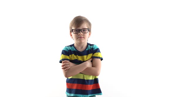 Little Schoolboy Poses in Studio on a White Background, Raises His Hand with a Finger at the Top