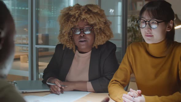 Businessman Talking with Diverse Female Colleagues at Night Office Meeting alt