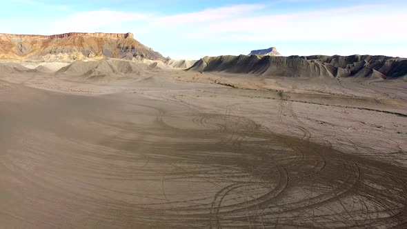 Flying over desert landscape covered in tire tracks alt