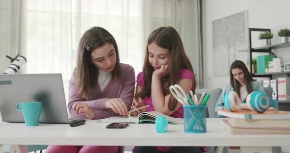 Girl helping her younger sister with her homework, they are studying together