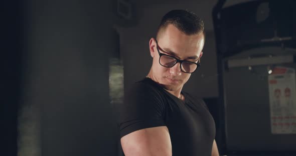 Man with Glasses Pulling Loop with Hand for Arm Muscles at Simulator in Gym alt