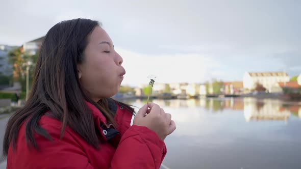 Asian woman blowing pollen beside the river on the weekend alt