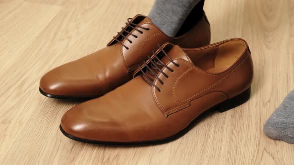 Man to wear his elegant brown shoes. Close up