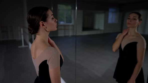 Side View Slim Young Woman Looking at Reflection in Mirror Standing in Dance Studio Smiling alt