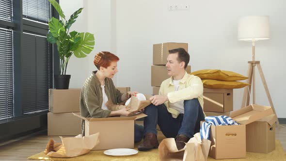 Caucasian Family Moving to New Apartment Surrounded with Plenty of Cardboard Boxes