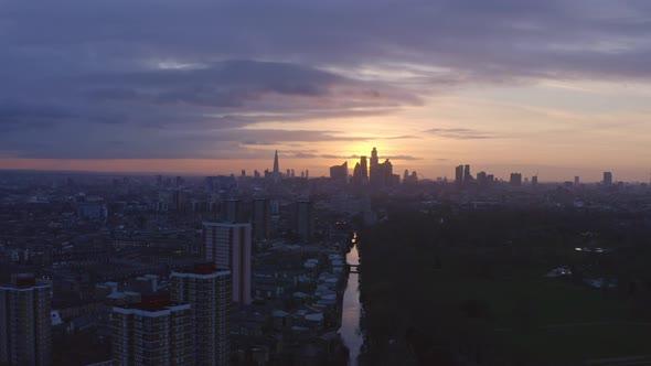 telephoto dolly back Aerial drone shot of London Canal towards city skyline at sunset alt