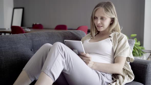 Smiling Pregnant Woman Using Tablet alt