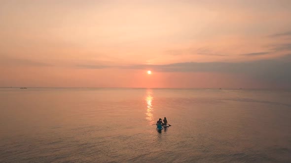 Two Young Women Enjoying an Incredible Orange Sunset in the Ocean