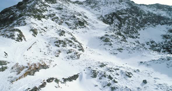 Forward Aerial Over Winter Snowy Mountain with Mountaineering Skier People Walking Up Climbing