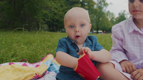 Children are Happy to Eat Fried French Fries While Sitting in Nature in the Park alt