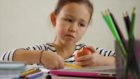 Ethnic Girl Doing Homework and Eating Apple