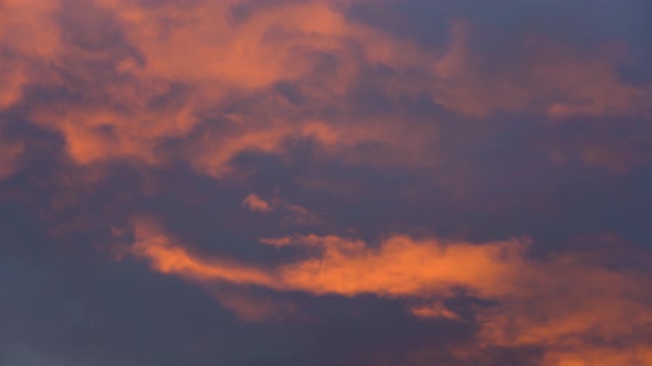 Yellow-Orange Dramatic Clouds Glowing Rays at Sunset Floating Across Dark Purple and Violet Sky