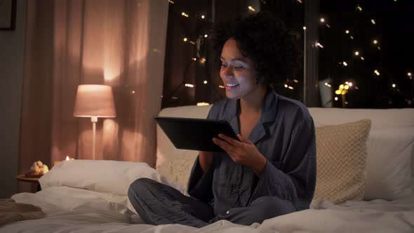 Happy Woman with Tablet Pc Sitting in Bed at Night alt