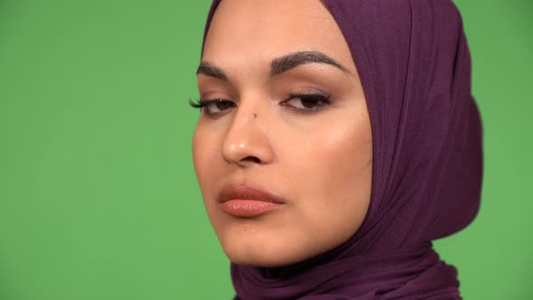 A Young Beautiful Muslim Woman Looks Seriously at the Camera  Face Closeup Green Screen Background