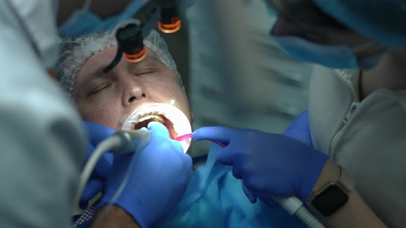 Headshot of Caucasian Man with Mouth Retractor Opening Eyes As Dentist Leaving with Drill and alt