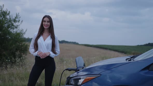 Girl Stands on Her Electric Car That Charges alt