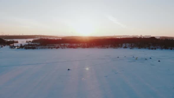 Beautiful Aerial View of Campground on Frozen Lake in Rays of Setting Sun alt