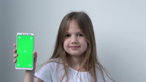 Cute Child Girl Shows Phone with Green Screen Mock Up Cellphone Mobile Telephone alt