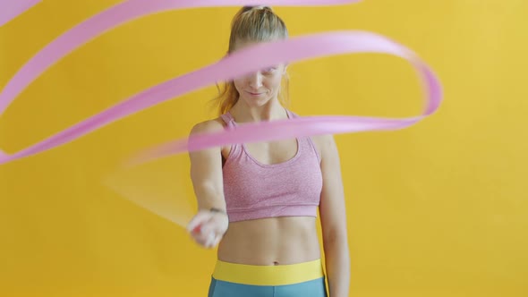 Portrait of Beautiful Young Woman in Sports Bra Moving Artistic Gymnastics Ribbon alt